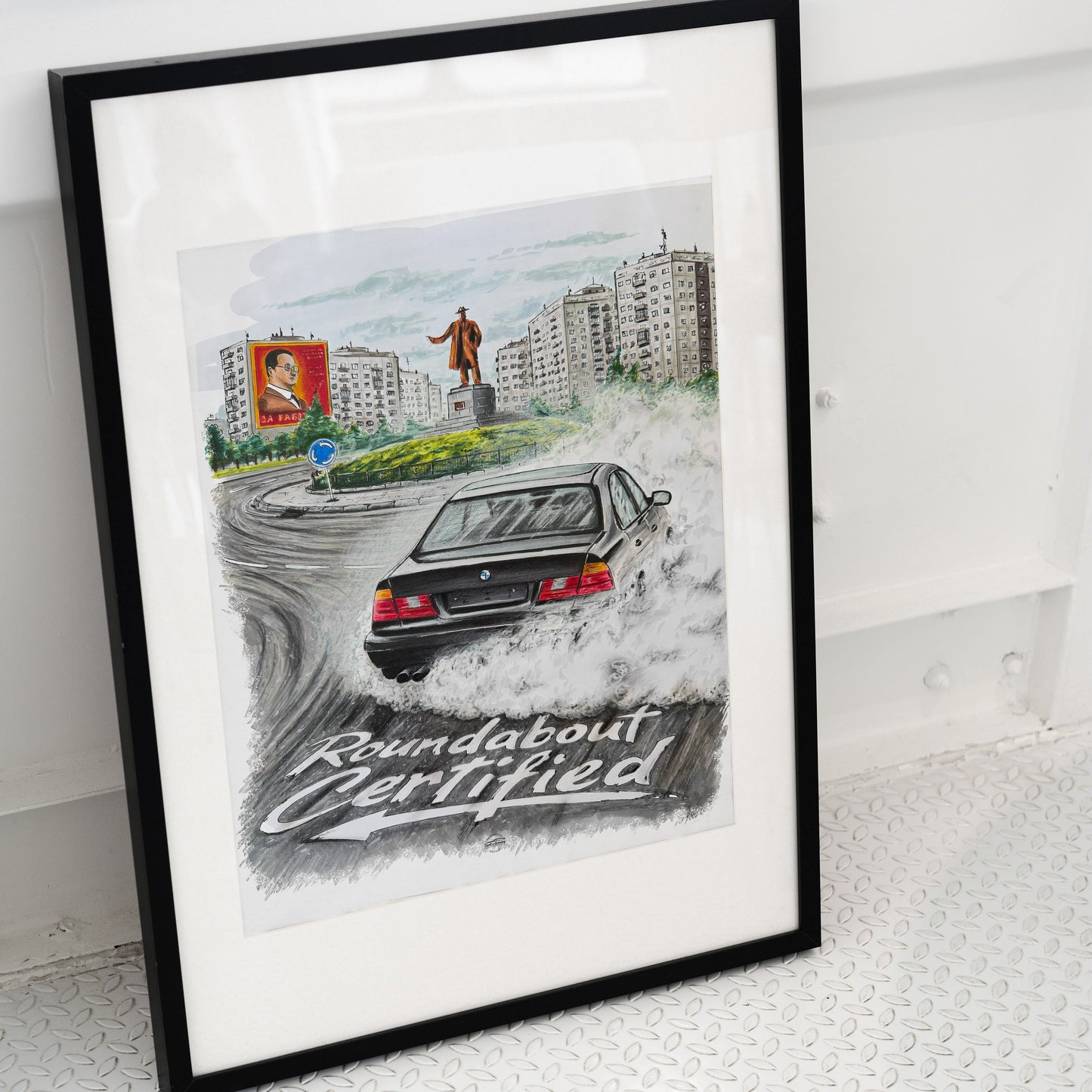 Framed artwork of a bmw e34 on a roundabout with a cityscape background, featuring the text 'Roundabout Certified'.