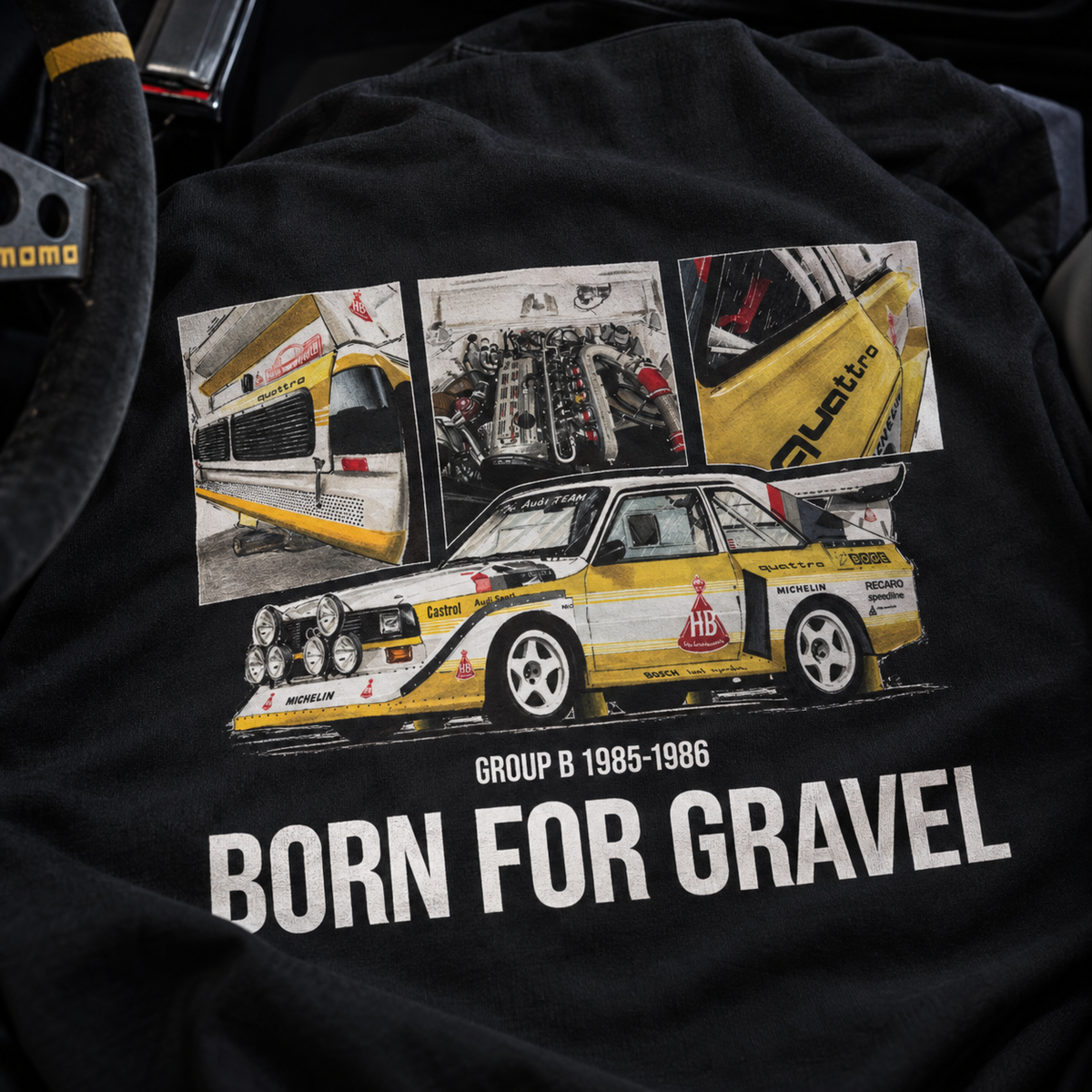 A close-up of a black hoodie featuring a large graphic print of a Audi Quattro Group B race car with three inset photos above it. The text 'GROUP B 1985-1986' and 'BORN FOR GRAVEL' are printed in white below the car.