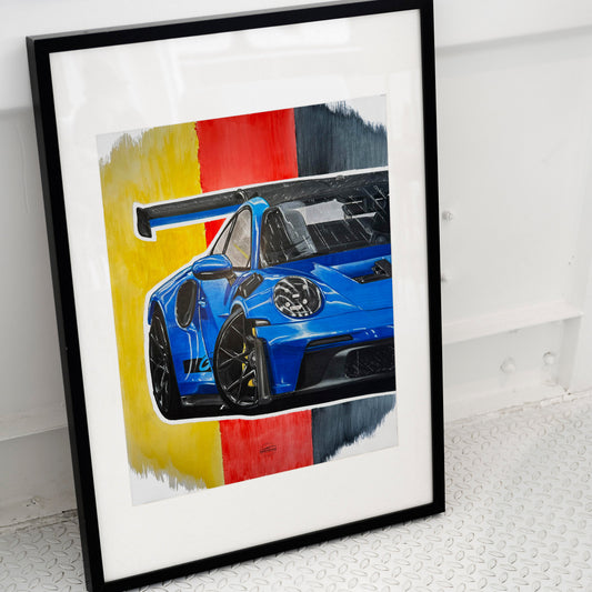Framed artwork of a blue Porsche GT3RS placed on ground.