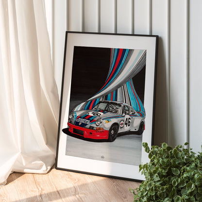 A framed art print leaning against a white paneled wall on a light wood floor, next to a white curtain and a green plant. The print features a vintage race Porsche Carerra car with colorful abstract flowing lines in the background.