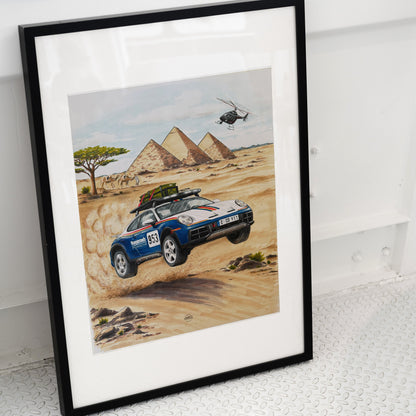 Framed artwork of a Porsche 911 Dakar car in a desert with pyramids and a helicopter.