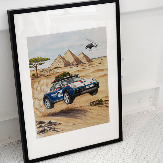 Framed artwork of a Porsche 911 Dakar car in a desert with pyramids and a helicopter.